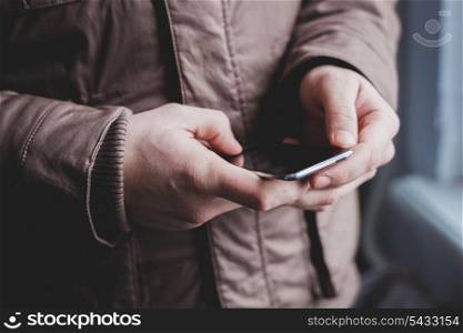 The man is using a smartphone. Modern mobile phone in hand.