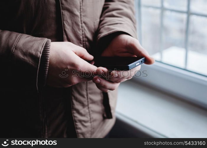 The man is using a smartphone. Modern mobile phone in hand.