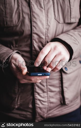 The man is using a smartphone. Modern mobile phone in hand.