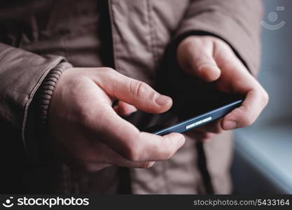 The man is using a smartphone. Modern mobile phone in hand.