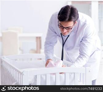 The man male pediatrician near baby bed preparing to examine. Man male pediatrician near baby bed preparing to examine