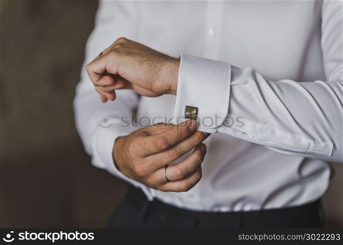 The man pulls out a box of cuff links.. Young businessman wears cufflinks on the lapels of his shirt 547.