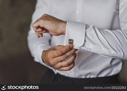 The man pulls out a box of cuff links.. Young businessman wears cufflinks on the lapels of his shirt 547.