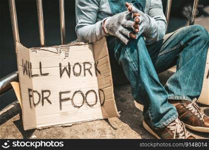 The man sitting begging on an overpass with messages homeless people please help and work well with food.