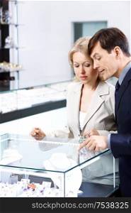 The man specifies to the woman in a jewel in shop