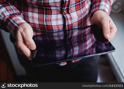 The man uses a tablet PC. Modern gadget in hand.