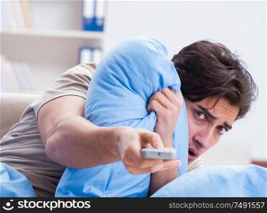 The man watching tv from bed holding remote control unit. Man watching tv from bed holding remote control unit