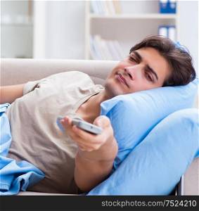 The man watching tv from bed holding remote control unit. Man watching tv from bed holding remote control unit