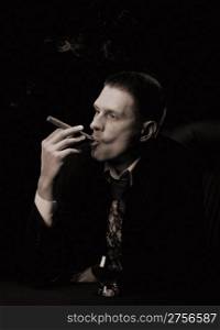 The man with a cigar and a glass of cognac. Monochrome tone. A dark background