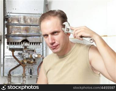 The man with a wrench thinks of repair of a gas water heater