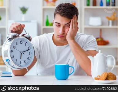 The man with alarm clock falling asleep at breakfast. Man with alarm clock falling asleep at breakfast
