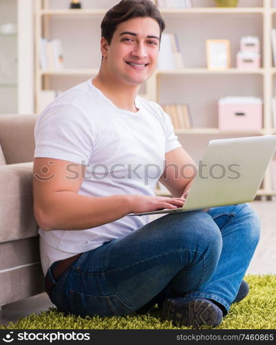 The man working on laptop at home on carpet floor. Man working on laptop at home on carpet floor