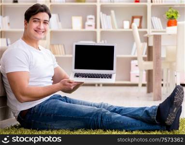 The man working on laptop at home on carpet floor. Man working on laptop at home on carpet floor