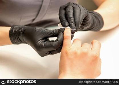 The manicurist finishes the procedure for red nail polishing and cleaning with a cotton napkin, pad, swab in a beauty salon, close up. The manicurist finishes the procedure for red nail polishing and cleaning with a cotton napkin, pad, swab in a beauty salon, close up.