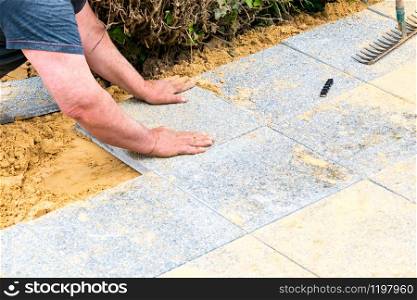 the mason lays gravel slabs on sand to make an alley