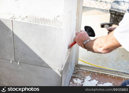 the mason prepares the wall with a chisel before laying a ceramic tile