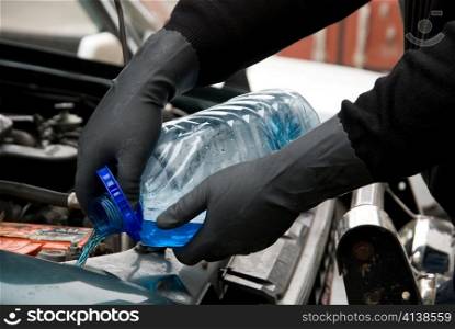 The mechanic fills washing liquid to the car