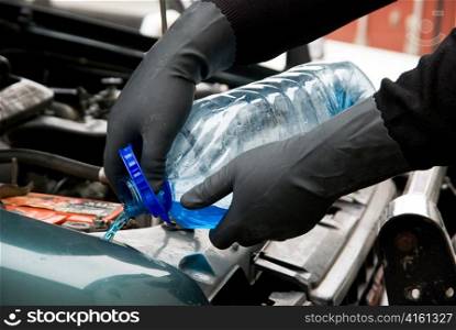 The mechanic fills washing liquid to the car