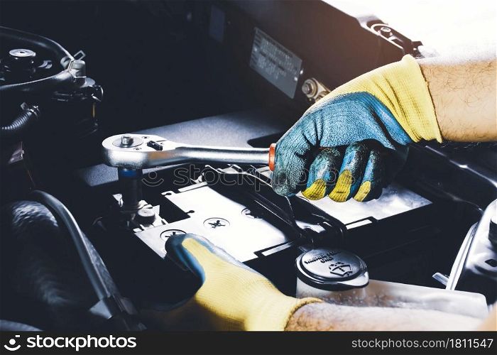 The Mechanic hand is fasten the bolt of battery Anode with socket wrench