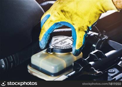 The mechanic hand is open or close the cap of the power steering fluid to check the hydraulic fluid level