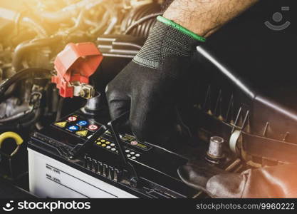 The Mechanic hand is pulling up an car old battery for replacement