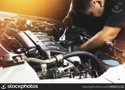 The Mechanic hand wearing black gloves is fasten the bolt with the socket wrench to repairing of the car engine