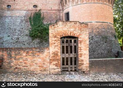 The medieval brick walls of the small village of Dozza near Bologna in Emilia Romagna, Italy. wood fence as door