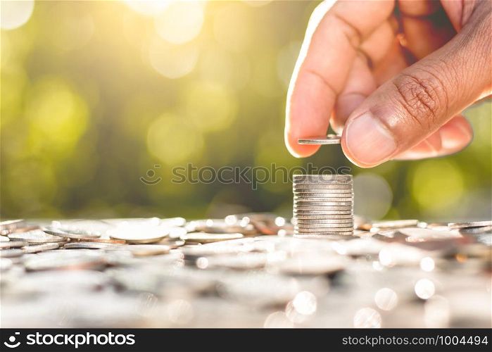The men's right hand is stacked with coins and coins are scattered at the bottom with morning sunlight shinning.