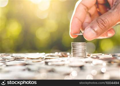 The men's right hand is stacked with coins and coins are scattered at the bottom with morning sunlight shinning.