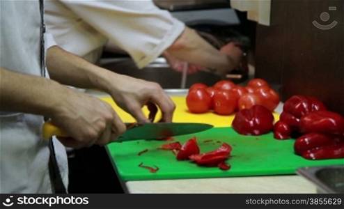 The men slicing a red pepper, close-up view.