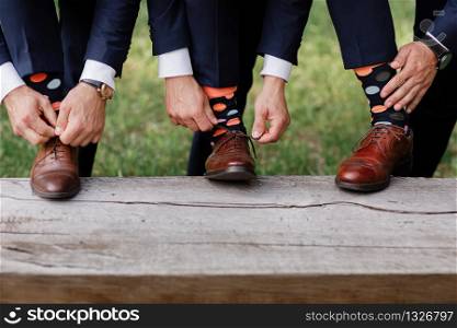 The men wears shoes with stylish socks. Stylish suitcase, men&rsquo;s legs, multicolored socks and new shoes. Concept of style, fashion, beauty and vacation. Tie the laces on the shoes. The men wears shoes with stylish socks. Stylish suitcase, men&rsquo;s legs, multicolored socks and new shoes. Concept of style, fashion, beauty and vacation. Tie the laces on the shoes.