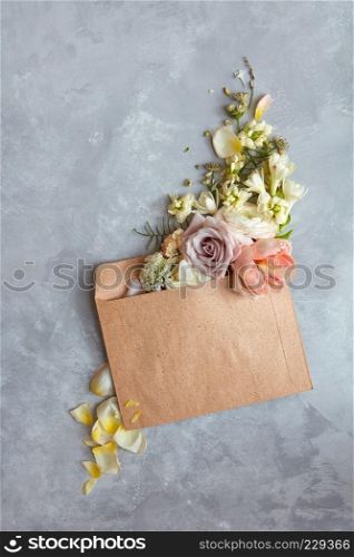 The message in the letter. Beautiful bouquet of flowers in an envelope on a stone gray background as a concept for the holiday, Flat lay.. Flowers in envelope