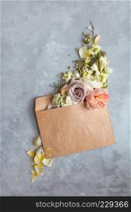 The message in the letter. Beautiful bouquet of flowers in an envelope on a stone gray background as a concept for the holiday, Flat lay.. Flowers in envelope