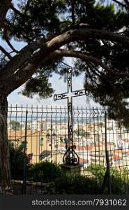 The metal cross is located under a huge pine tree overlooking the old town of Cannes in France