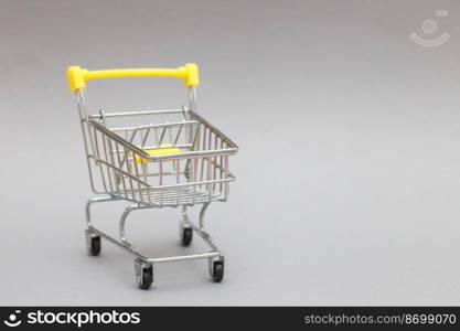 The metal shopping cart on a grey background. The metal shopping cart on a grey background.