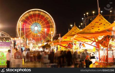 The midway is all lit up at night with motion occuring in this long exposure at the state fair