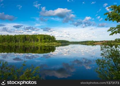The mirror surface of the river with reflection of clouds in the quiet summer morning.