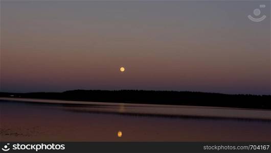 the moon hangs over the lake