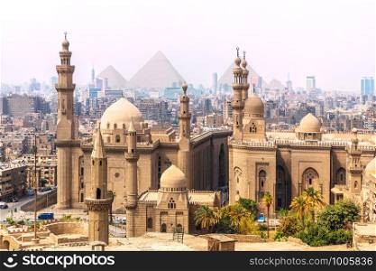 The Mosque-Madrassa of Sultan Hassan and the Pyramids in the background, Cairo, Egypt.. The Mosque-Madrassa of Sultan Hassan and the Pyramids in the background, Cairo, Egypt