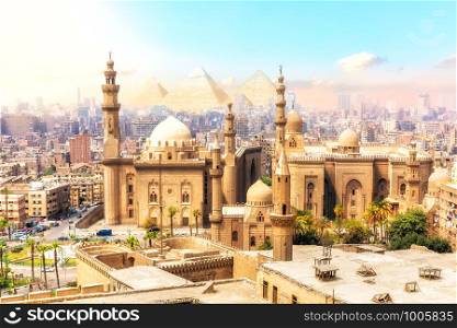 The Mosque-Madrassa of Sultan Hassan and the Pyramids on the background, beautiful view of Cairo, Egypt.. The Mosque-Madrassa of Sultan Hassan and the Pyramids on the background, beautiful view of Cairo, Egypt
