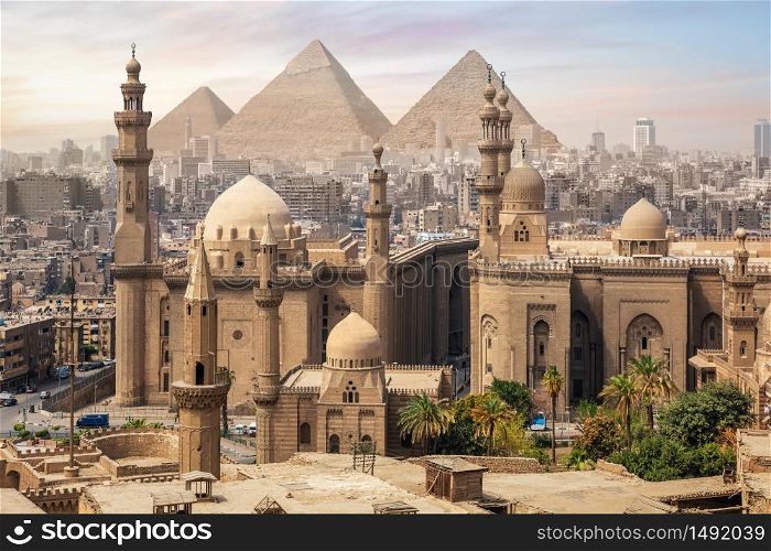 The Mosque of Sultan Hassan and the Great Pyramids of Giza, Cairo skyline, Egypt.