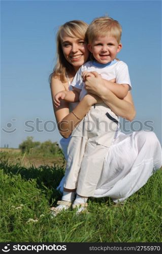 The mother and son. Happy people on a meadow with the clear blue sky