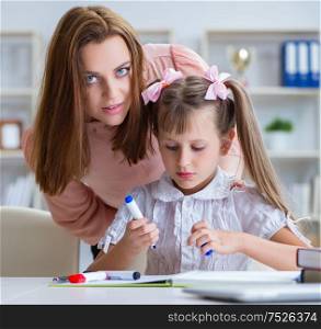 The mother helping her daughter to do homework. Mother helping her daughter to do homework