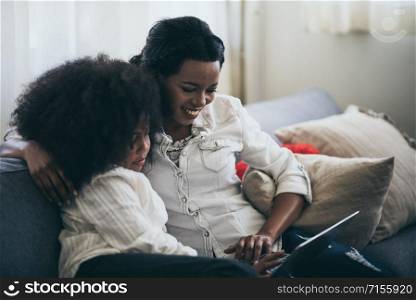 The mother is teaching homework to an African daughter.