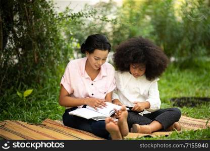 The mother is teaching homework to an African daughter.