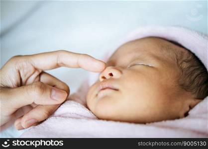 The mother&rsquo;s hand touches the nose of the newborn baby.