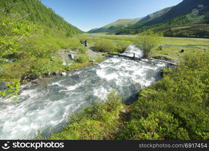 The mountain river in the mountains. Current through the gorge the river. Stones and rocky land near the river. Beautiful mountain landscape. The mountain river in the mountains. Current through the gorge the river. Stones and rocky land near the river. Beautiful mountain landscape.