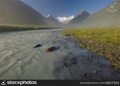The mountain river in the mountains. Current through the gorge the river. Stones and rocky land near the river. Beautiful mountain landscape. The mountain river in the mountains. Current through the gorge the river. Stones and rocky land near the river. Beautiful mountain landscape.