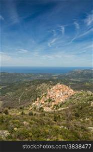 The mountain village of Speloncato in the Balagne region of north Corsica with maquis and the Mediterranean in the background against a blue sky and wispy clouds