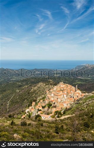 The mountain village of Speloncato in the Balagne region of north Corsica with maquis and the Mediterranean in the background against a blue sky and wispy clouds